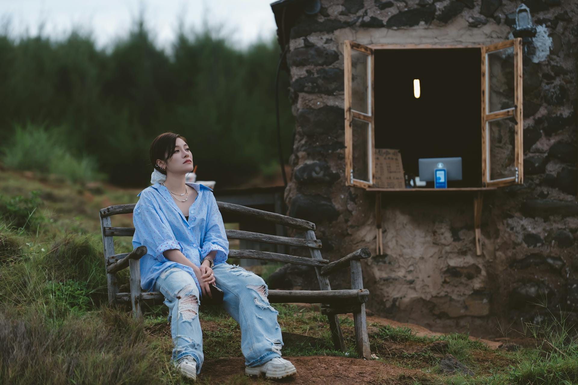 Femme assise sur un banc près d'une cabane.