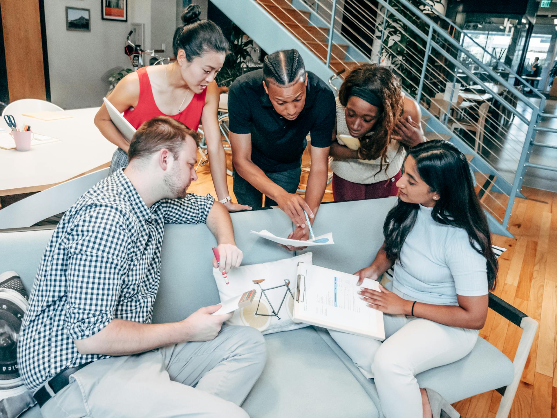 Groupe discutant autour de documents sur un canapé.