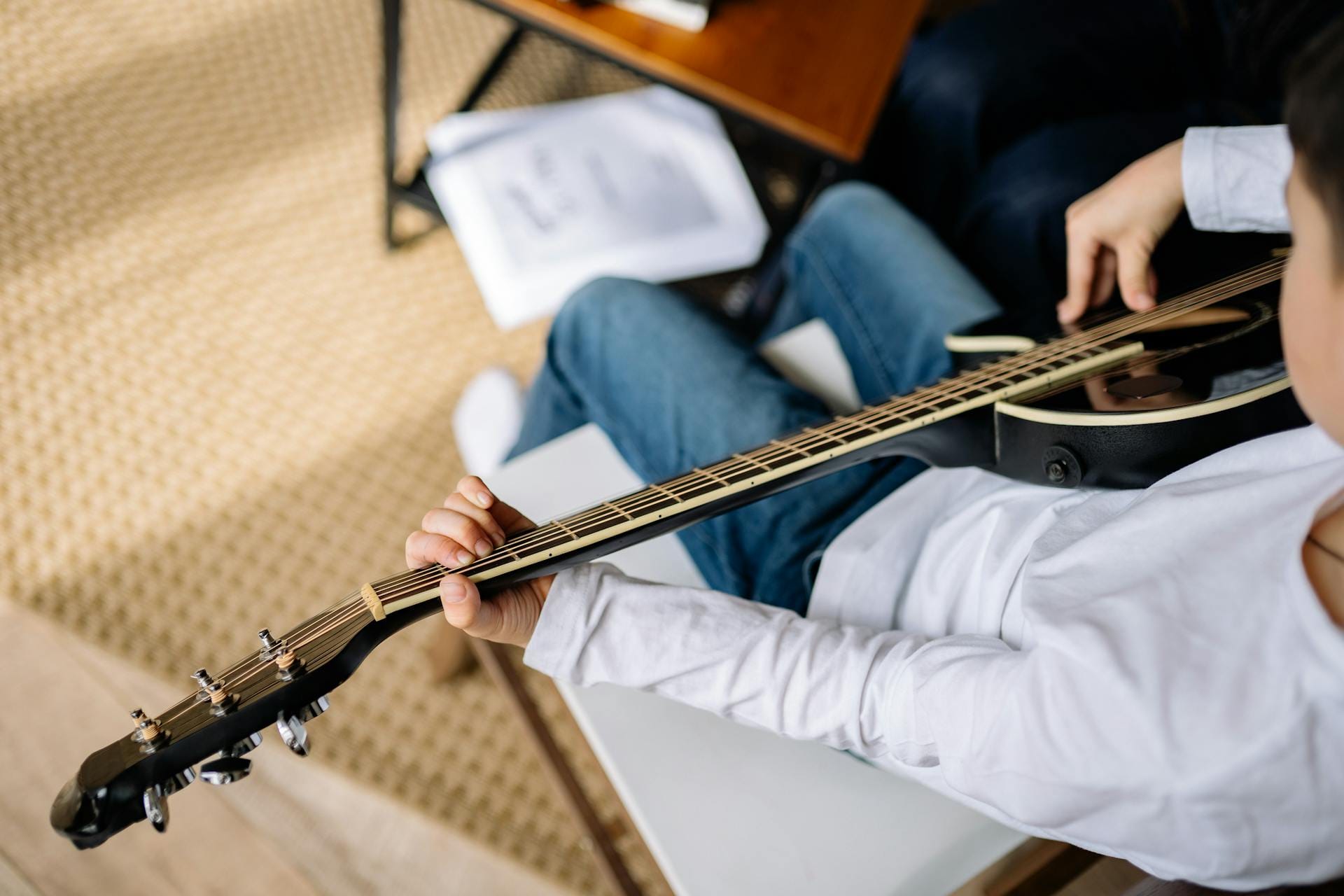Enfant jouant de la guitare électrique assis.