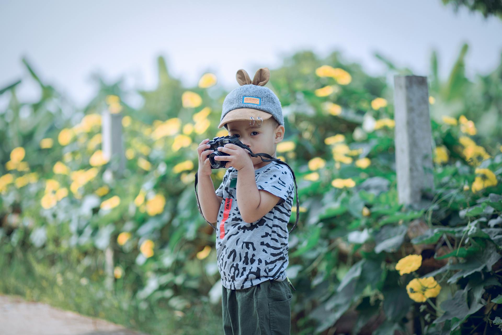 Enfant avec appareil photo dans un jardin fleuri.