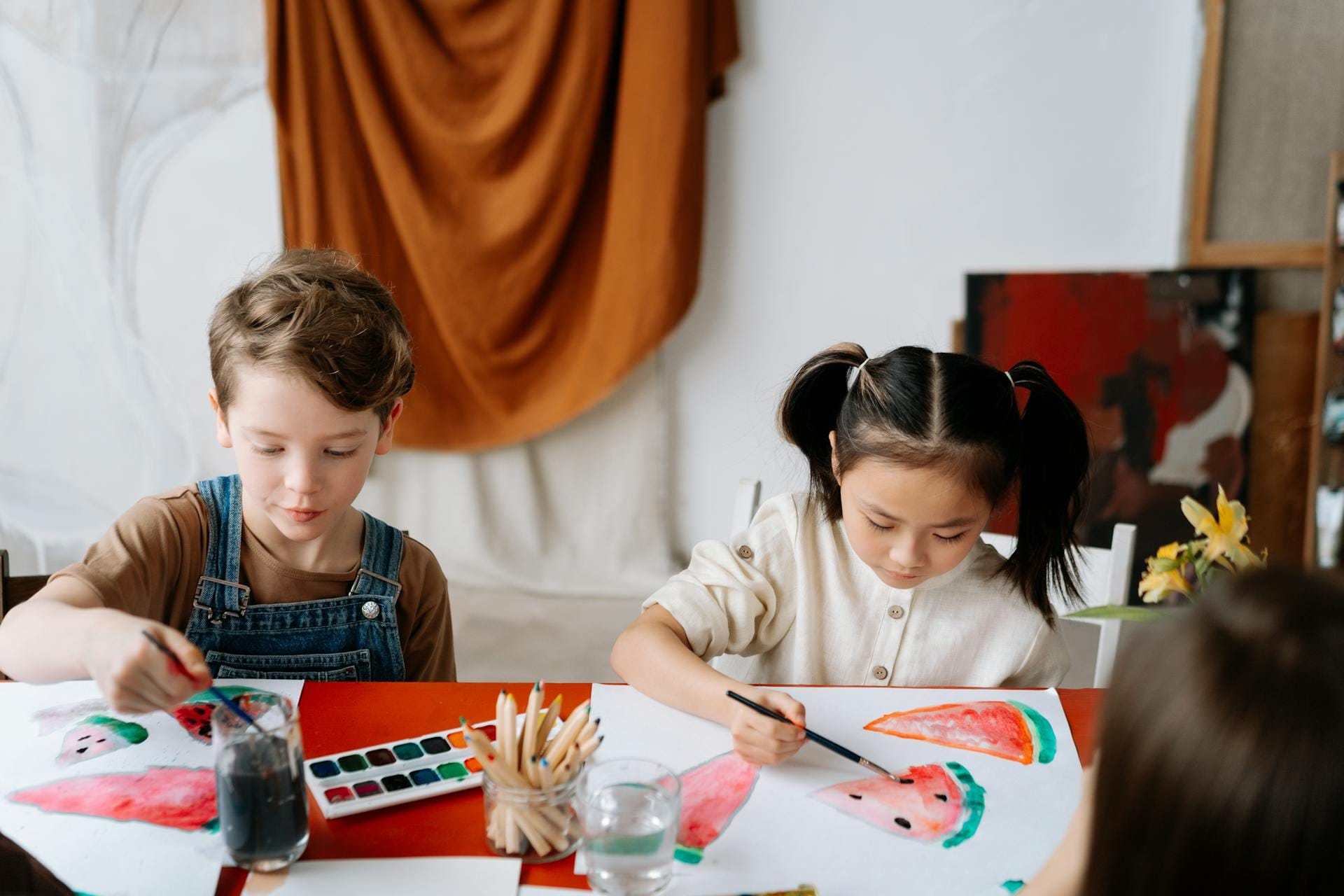Enfants peignant des pastèques avec des aquarelles.