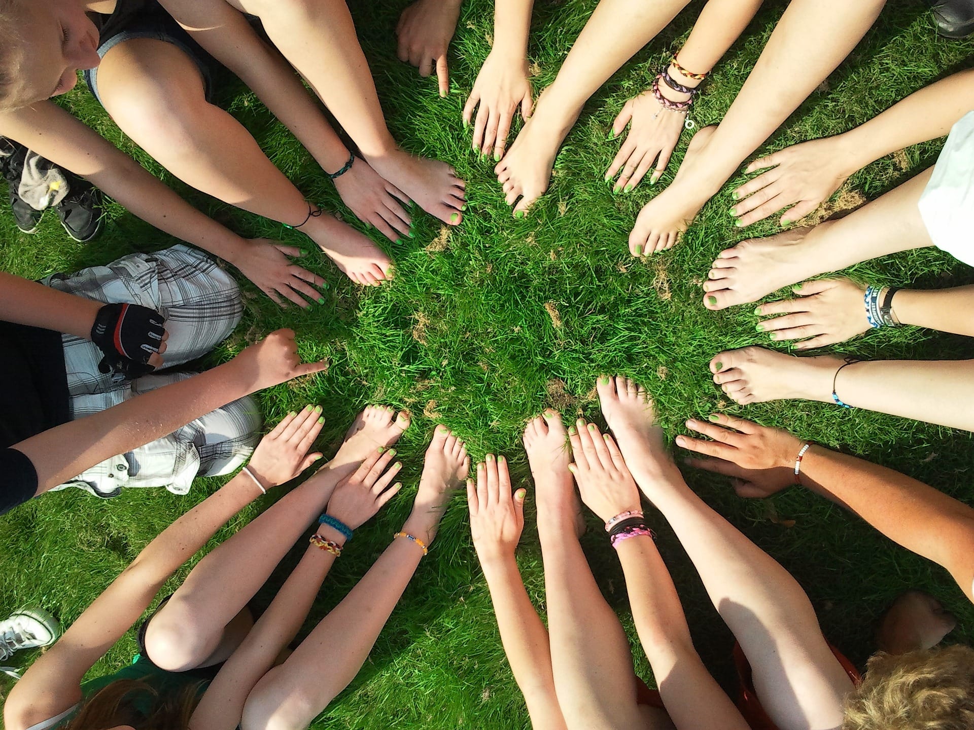 Mains et pieds au sol en cercle sur l'herbe.