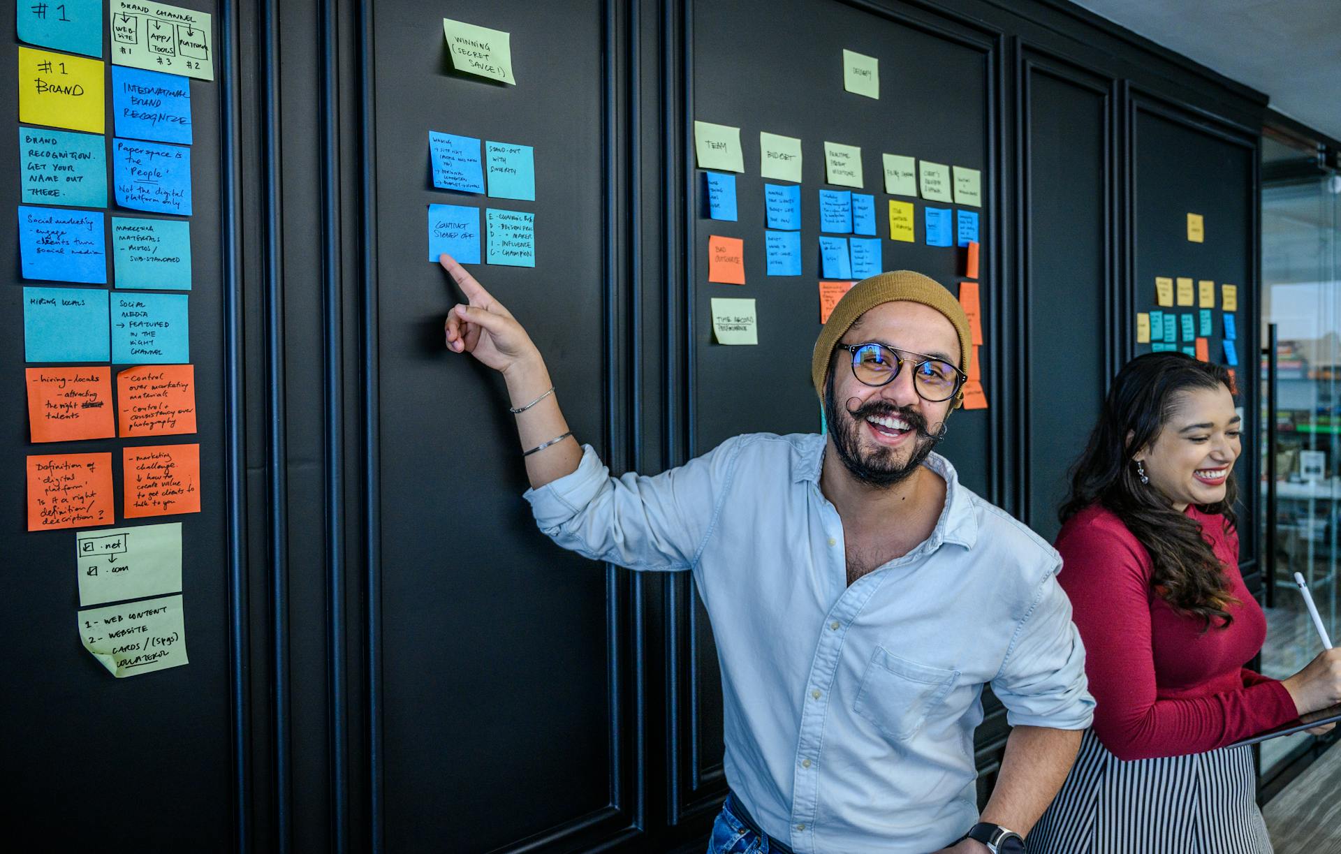 Personnes souriantes devant tableau avec notes colorées.