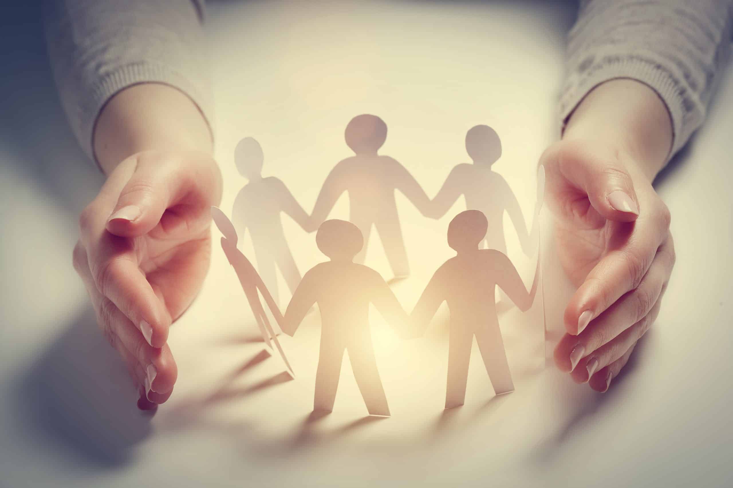 Figures en papier protégées par des mains.