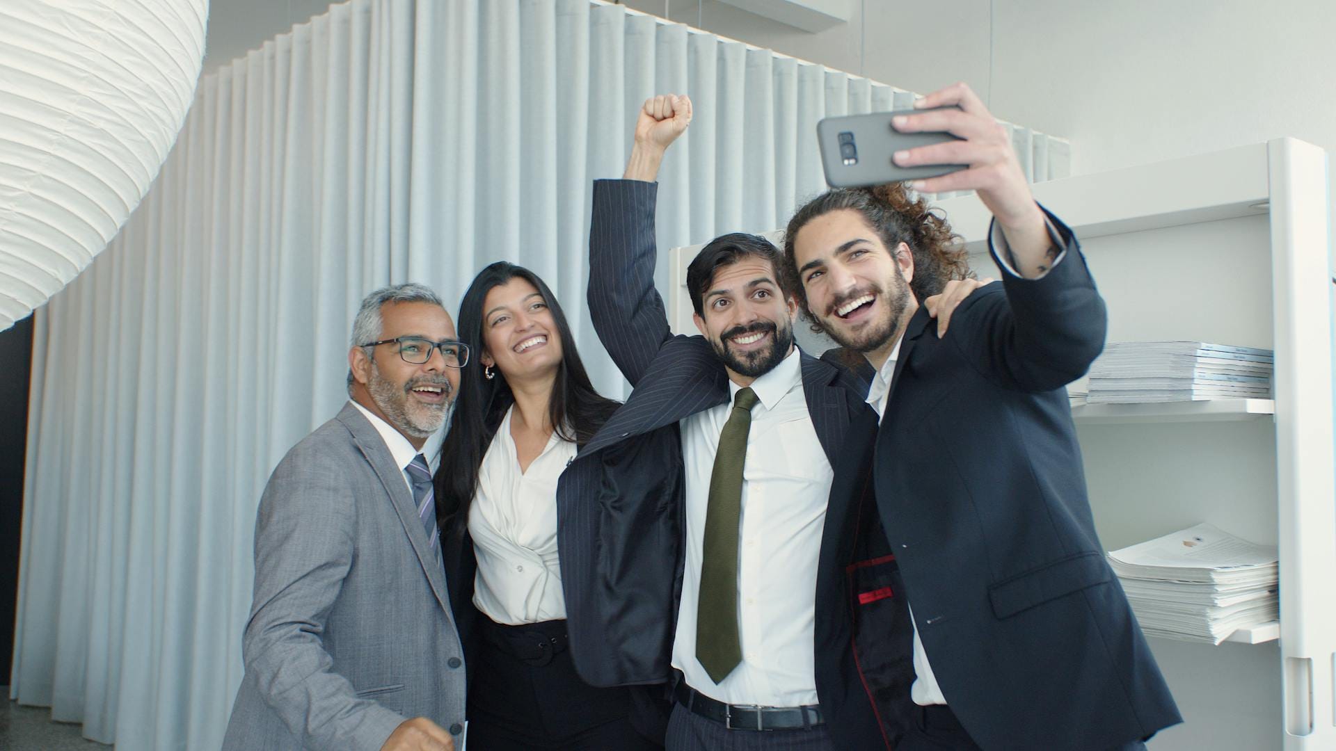 Groupe souriant prenant selfie au bureau.