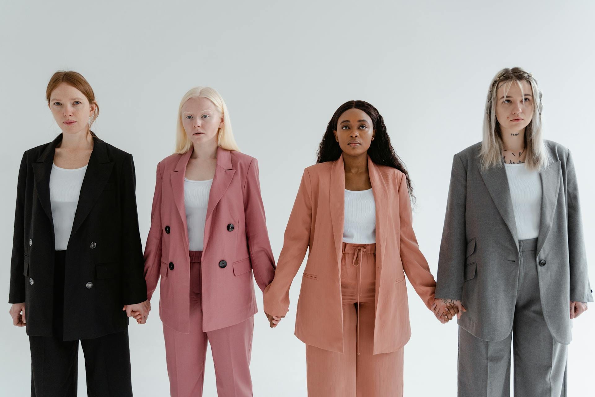 Quatre femmes en costume tiennent les mains.